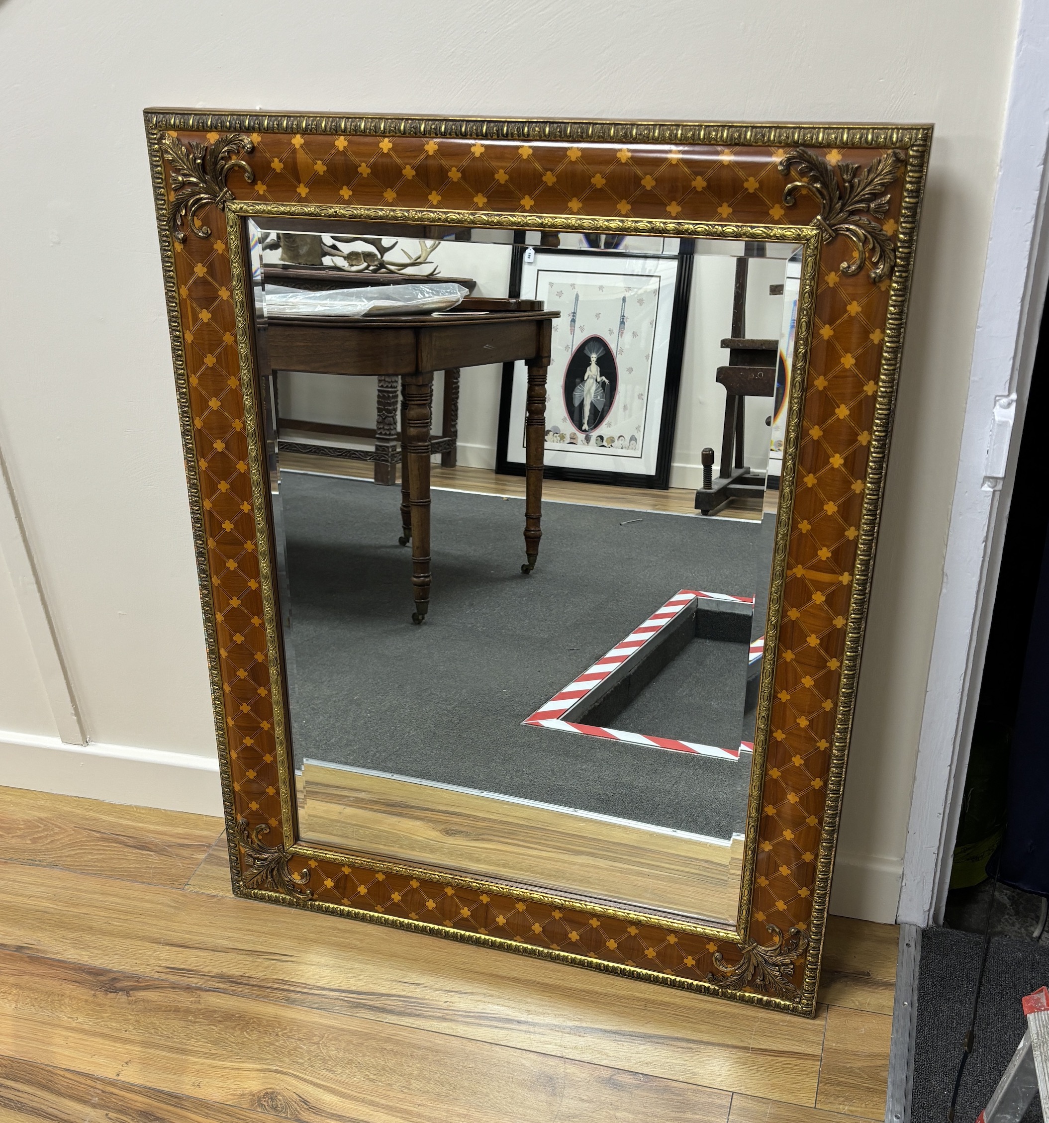 A bevelled wall mirror, the inlaid frame with trellis pattern and gilt metal mounts (purchased from Harrods), width 99cm, height 80cm